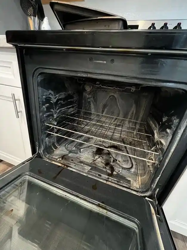 An oven interior coated in burnt grease and spills, before cleaning