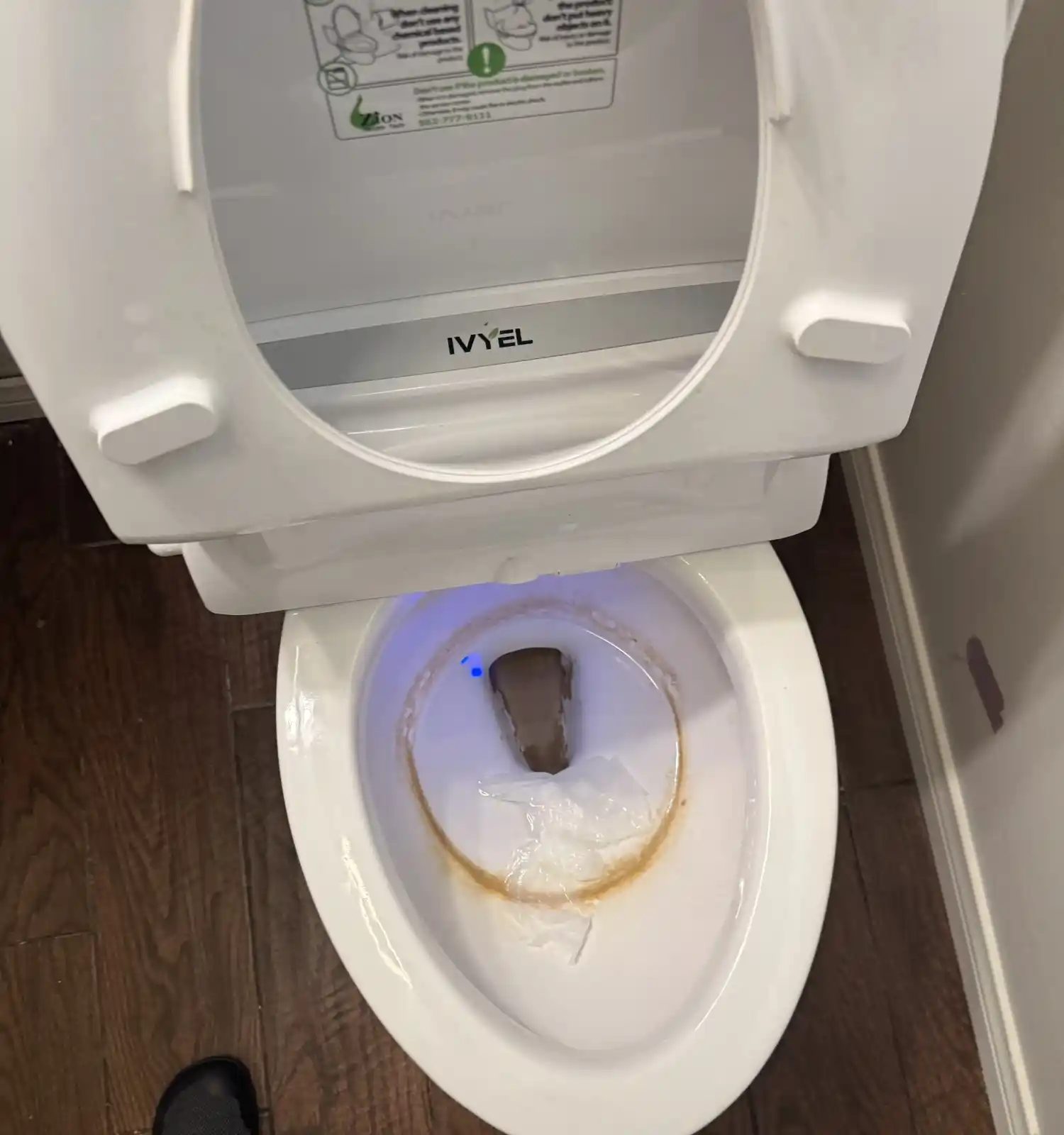 A toilet bowl with a rust-colored ring and stains, before cleaning